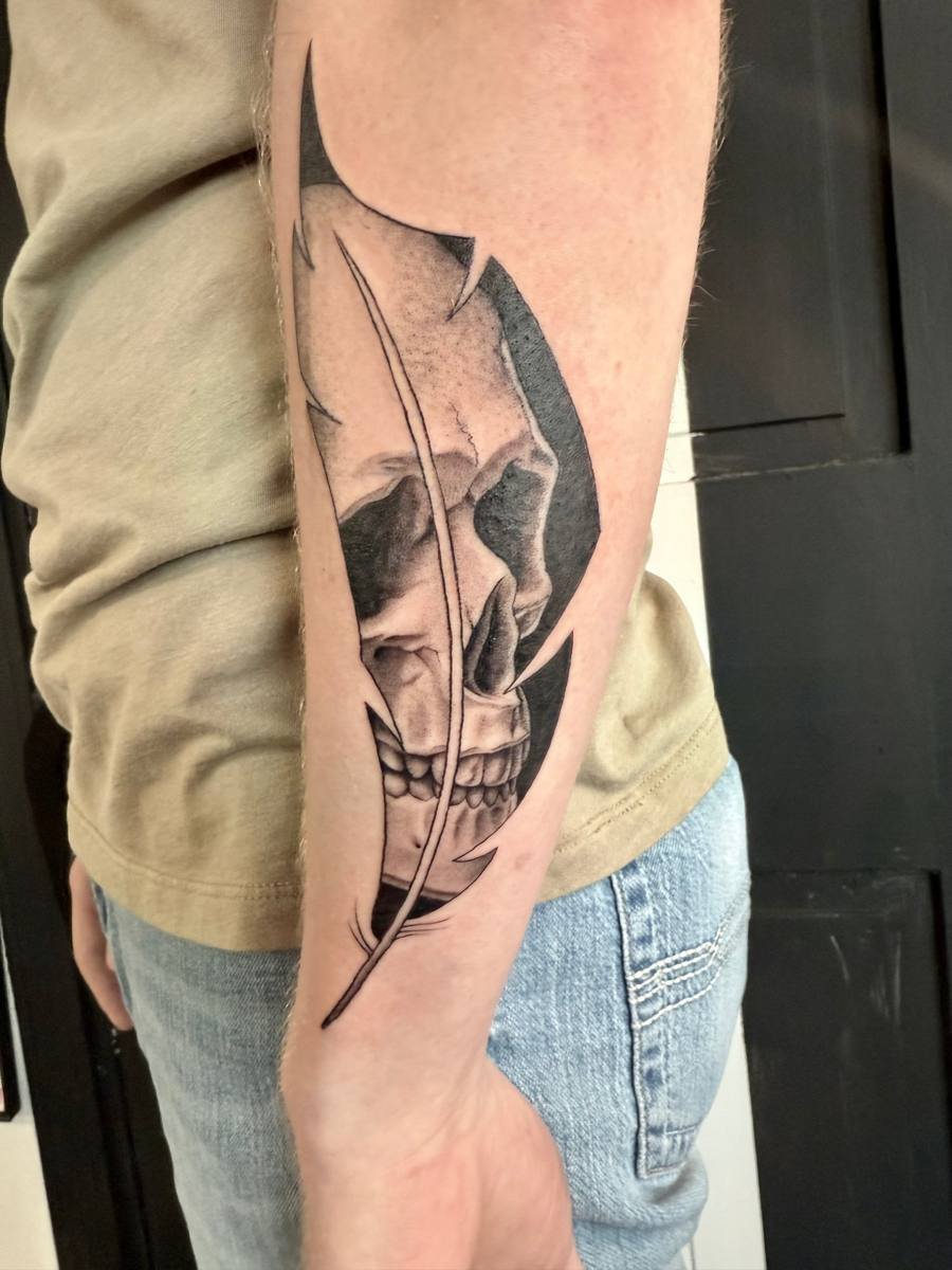 Skull inside a feather black and grey tattoo